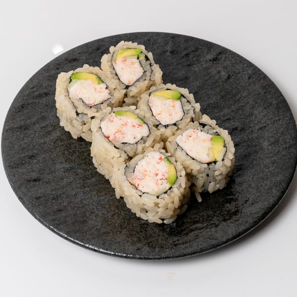 Six California rolls with crab and avocado, served on a dark gray plate.